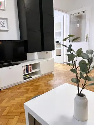 a living room with a white table and a tv at Fully Equipped - Cozy & Convenient City Apartment in Belgrade