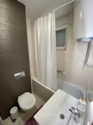 a white bathroom with a toilet and a sink at Anči apartmani in Belgrade