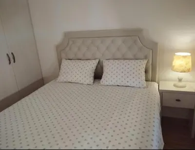a bed with two pillows and a lamp on a table at DomaćIN in Ledine