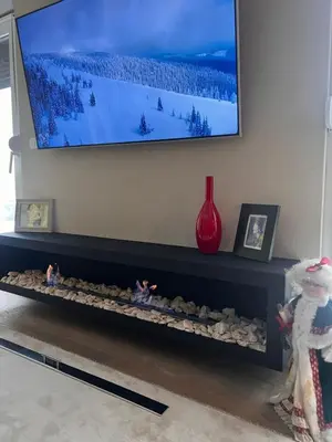 a flat screen tv above a fireplace with rocks at Autokomanda Large Family Apartment in Belgrade