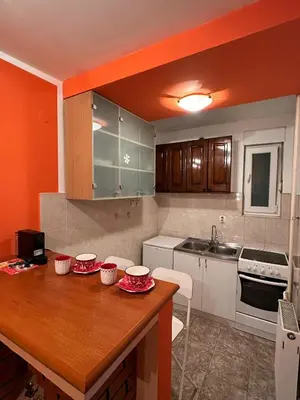 a kitchen with a wooden table with red dishes on it at Urban Nest - Orange in Belgrade