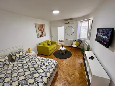 a bedroom with a bed and a yellow chair at Cozy Apartment in Belgrade Downtown in Belgrade
