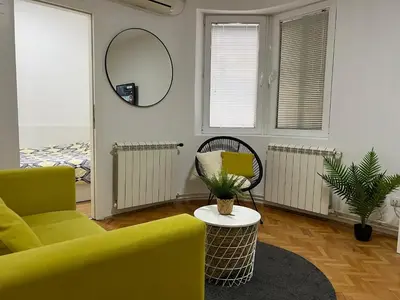 a living room with a yellow couch and a mirror at Cozy Apartment in Belgrade Downtown in Belgrade