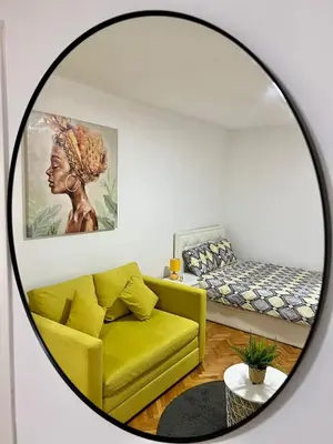 a mirror in a living room with a yellow couch at Cozy Apartment in Belgrade Downtown in Belgrade