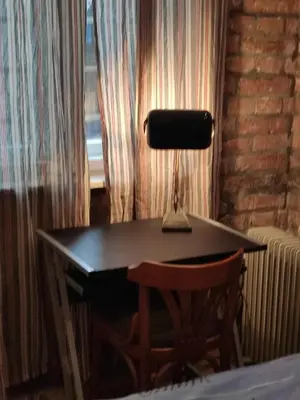 a desk with a lamp and a chair next to a window at Cosy City Hideway in Belgrade