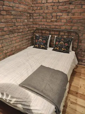 a bed with two pillows and a brick wall at Cosy City Hideway in Belgrade