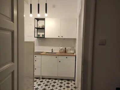 a kitchen with white cabinets and a black and white tile floor at Cosy City Hideway in Belgrade