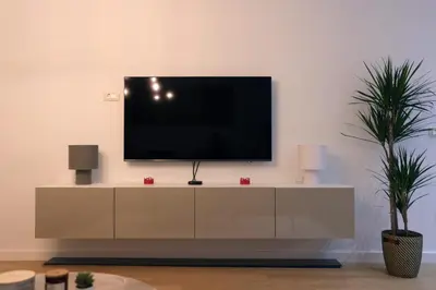 a tv on a white cabinet in a living room at Cityheart St. Sava in Vračar (historical)