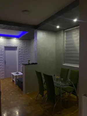 a dining room with a table and green chairs at Play Apartman Obrenovac in Obrenovac