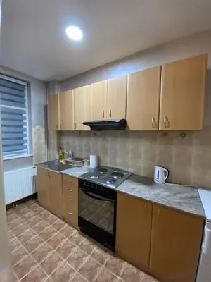 a kitchen with wooden cabinets and a stove top oven at Play Apartman Obrenovac in Obrenovac