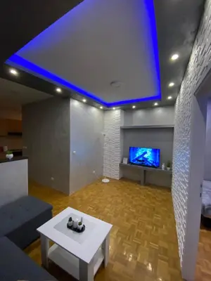 a living room with a white table and a tv at Play Apartman Obrenovac in Obrenovac