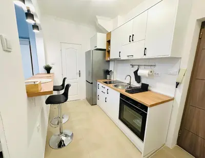 a kitchen with white cabinets and a sink and a stool at Golden Oasis in Belgrade