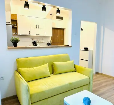 a living room with a yellow couch and a kitchen at Golden Oasis in Belgrade