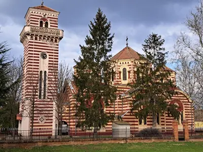 a building with a clock tower next to a tree at Eagles Court - Orlovski Vrt in Staji°evo