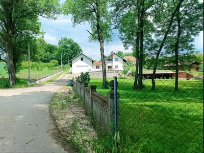 a fence in front of a field with a house at Jablanicki Refugium in Pružatovac