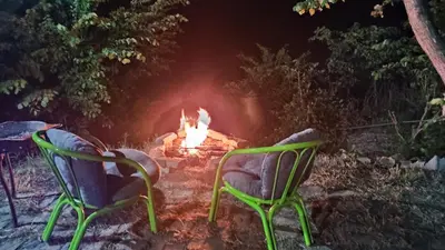 two green chairs sitting in front of a fire at Kuća za proslave i odmor ZMAJEVO GNEZDO in Pe°ani