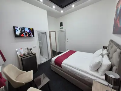 a hotel room with a bed and a tv on the wall at Authentic Belgrade Centre - 4 Suites in One Space, with patios in courtyard for smokers in Belgrade