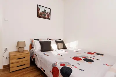 a white bedroom with a bed and a night stand at Apartman Aki in Bele Vode