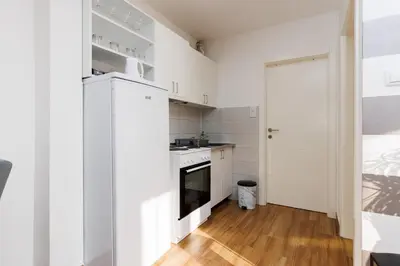 a small kitchen with white cabinets and a stove at Apartman Aki in Bele Vode