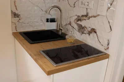 a kitchen counter with a sink and a marble wall at AIRPORT APARTMANI HAPPY HOUSE free parking & early check-in in Surčin