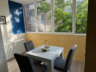 a white table and chairs in a room with windows at Modern one bedroom in the center of Belgrade in Belgrade