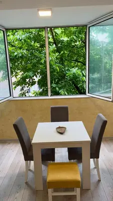 a table and chairs in a room with large windows at Modern one bedroom in the center of Belgrade in Belgrade