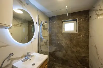 a bathroom with a sink and a shower and a mirror at Honey Spa house in Novi Slankamen