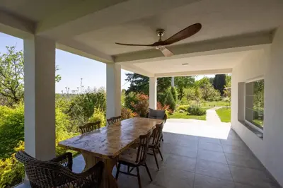 a patio with a table and chairs and a ceiling fan at Honey Spa house in Novi Slankamen