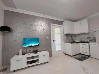 a kitchen with white cabinets and a tv on the wall at D&N Apartman in Ledine