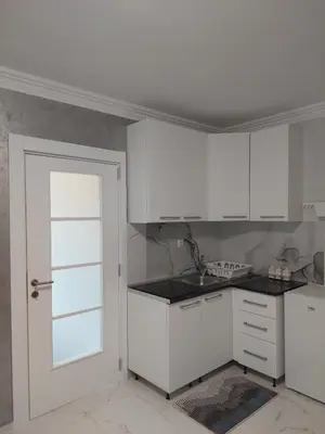 a white kitchen with white cabinets and a door at D&N Apartman in Ledine