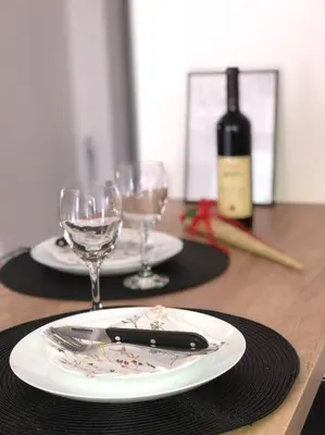 a wooden table with two plates and wine glasses at Blue apartman in Belgrade