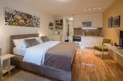 a bedroom with a large bed and a kitchen at Cozy studio with a terrace near Slavija square in Sajmište