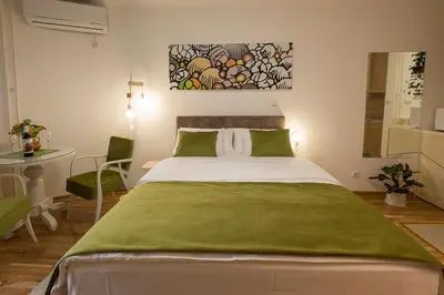 a bedroom with a large bed with a green blanket at Cozy studio with a terrace near Slavija square in Sajmište