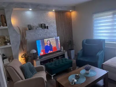 a living room with a tv and two blue chairs at Tea i Una in Arandjelovac