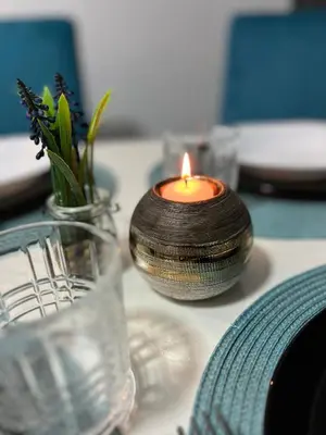 a candle sitting on a table with a vase of flowers at Tea i Una in Arandjelovac