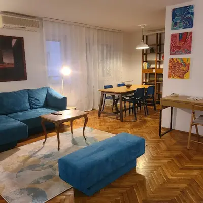 a living room with a blue couch and a table at Soulful Apartment Belgrade in Belgrade