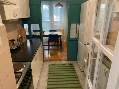 a kitchen with green and white cabinets and a table at Soulful Apartment Belgrade in Belgrade
