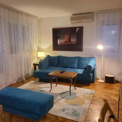 a living room with a blue couch and a table at Soulful Apartment Belgrade in Belgrade