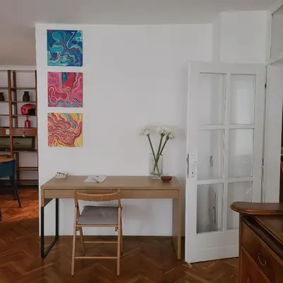 a desk with a vase of flowers on it in a room at Soulful Apartment Belgrade in Belgrade