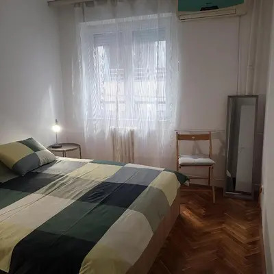 a bedroom with a bed and a window and a chair at Soulful Apartment Belgrade in Belgrade