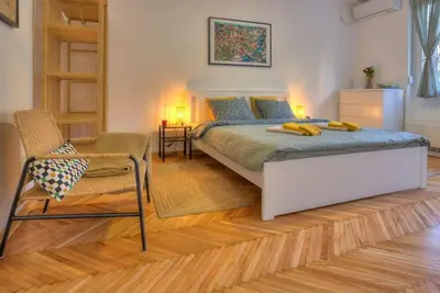 a bedroom with a large bed and a chair at Dorćol Central Apartment-NEW in Belgrade
