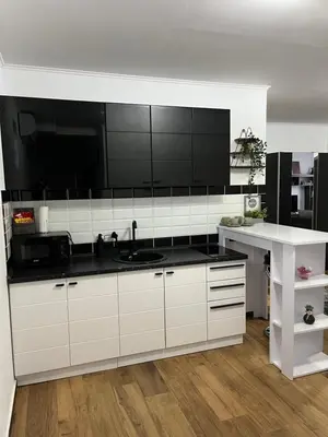 a kitchen with white cabinets and a black counter top at Airport SKY apartments LUX in Belgrade