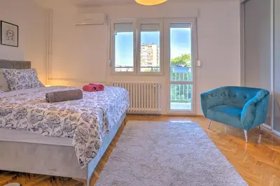 a bedroom with a bed and a blue chair at City View in Dušanovac (historical)