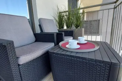 a table with two coffee cups and a chair on a balcony at BW Central View - Belgrade Waterfront in Belgrade