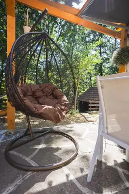 a wicker rocking chair sitting on a patio at Vikendica WoodNook Kosmaj - Šumski kutak in Sopot