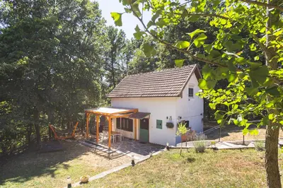 a small white house in a yard with trees at Vikendica WoodNook Kosmaj - Šumski kutak in Sopot
