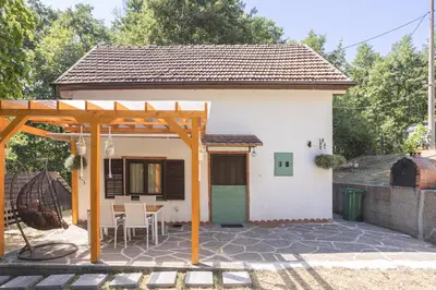 a small white house with a table and chairs at Vikendica WoodNook Kosmaj - Šumski kutak in Sopot
