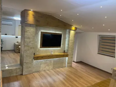 a living room with a tv on a stone wall at Apartman Maki in Pančevo