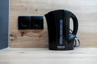 a black coffee cup next to an electrical outlet at Belgrade Apartment Nook in Belgrade