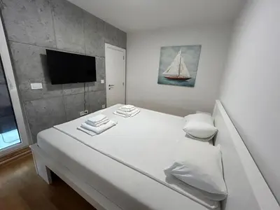 a bedroom with a white bed with a sailboat on the wall at Apartman ARISTEA in Arandjelovac